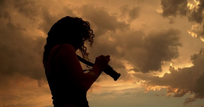 Silhouette of a woman photographer with a camera in nature during sunset. Freelance, content creator, blogger