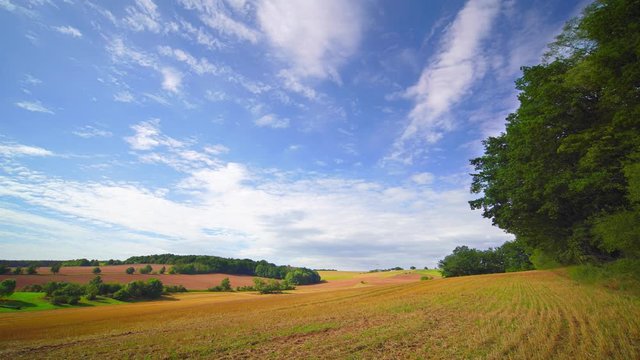 Time lapse of rolling clouds on blue sky over green field background