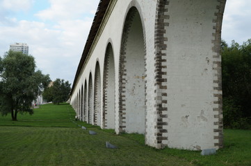 A perspective view of the aqueduct of white stone, surrounded by green grass and trees