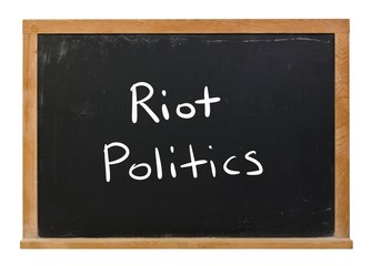 Obraz premium Riot politics written in white chalk on a black chalkboard isolated on white