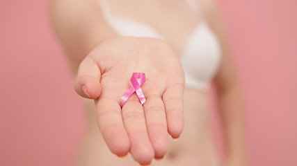 Woman in bra with pink ribbon, breast cancer survivor, pink october, awareness month. High quality photo