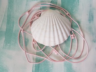 big white shell with pink pearls on turquoise background