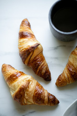 Coffee and croissant on white marble background. French breakfast. Top view flat lay with copy space