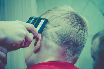 Obraz premium Haircut of a European blond boy's hair with a hair clipper. The image on the head of a child, a person in the form of a spider's web.