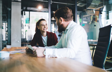 Cheerful adult male and female workers sitting at meeting room in company