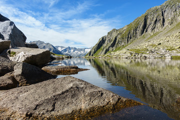 Bergsee mit Spiegelung eines Gebirges im Hintergrund in Tirol &Ouml;sterreich