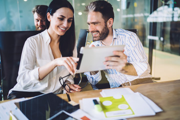 Laughing colleagues discussing work related information on tablet