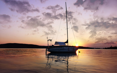 A sailboat anchored in a bay  on sunset