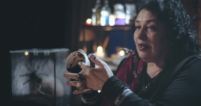 Old gypsy witch reading coffee grounds in empty cup