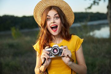 Surprised woman with camera yellow t-shirt hat summer nature lifestyle