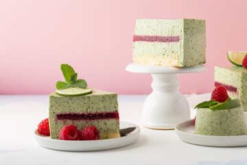 Pistachio mousse cake, cheesecake with fresh raspberry on white plate with mint leaves