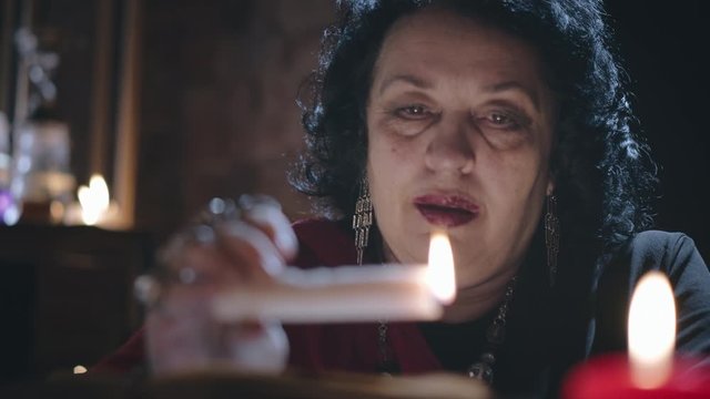 Old gypsy witch casting spell using burning candle