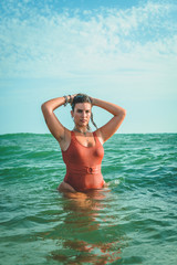 Beautiful young European woman with an orange swimsuit at the sea in Cádiz