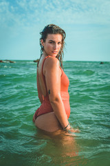 Beautiful young European woman with an orange swimsuit at the sea in Cádiz