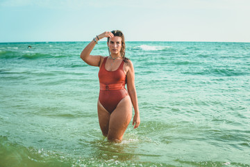 Beautiful young European woman with an orange swimsuit at the sea in Cádiz