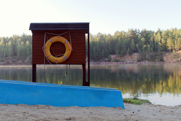 lifebuoy and overturned boat on the bank of forest lake on summer morning