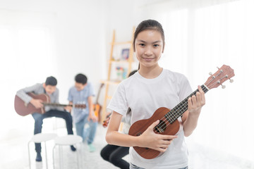 Fototapeta na wymiar cute asian children playing ukulele, she learning and training music education in her room, she feeling happy and smile in training time