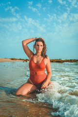Beautiful young European woman with an orange swimsuit on a beach in Cádiz