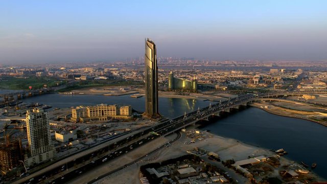 An aerial shot glancing at the Business Bay crossing bridge which is right by the Palazzo Versace and the Jaddaf Waterfront Marina, Aerial, 6-axis stabilized gimbal, Shotover F1, 8K, parallax.