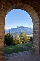 view of the snowy pyrenees through the stone arch of a church          