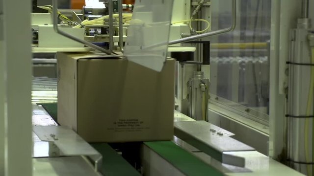 Smart automated warehouse box sealing system tapes and labels packages on conveyor roller for shipping.
