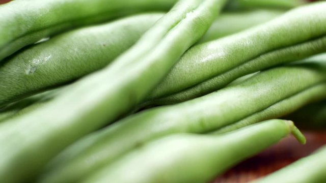 Raw fresh uncooked string beans on wooden kitchen surface close up selective focus