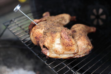 Meat thermometer in a chicken on the BBQ grill.
