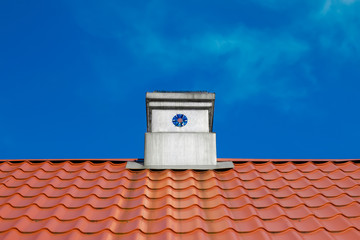 red tile roof with tin pipe against blue sky background