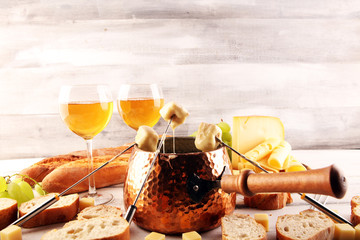 Gourmet Swiss fondue dinner on a winter evening with assorted cheeses on a board alongside a heated...