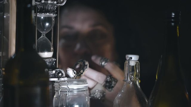 Witch holding snake and standing near apothecary jars for magic potions