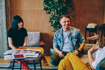 Cheerful Caucasian people discussing plan strategy for design project enjoying business meeting in loft flat, group of happy hipster guys 20s collaborating on creative ideas for new startup