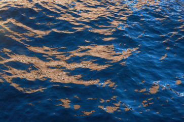 Smooth wavy water with reflection. Sky, and buildings reflected on the water surface. Selective focus