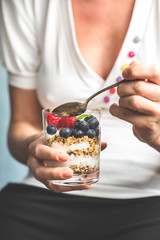 woman eating muesli with fruits. Healthy breakfast bowl. Yogurt, granola, seeds, fresh and dry fruits
