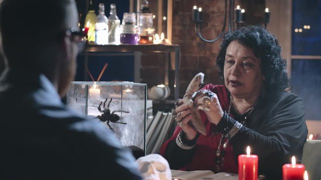 Witch talking to client about voodoo ritual with doll
