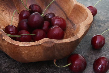 Red cherries in a wooden bowl on a brown background. Close-up. Summer and fresh berries