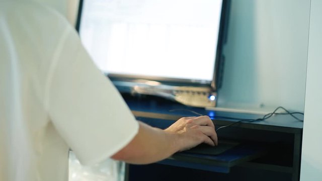 hand of a traumatologist uses a computer mouse, working with a computer - pictures of a bone fracture.