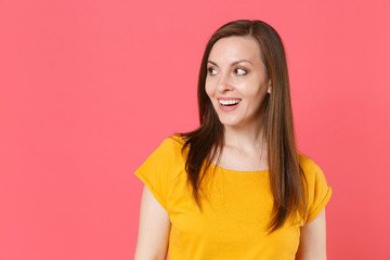 Fototapeta premium Excited cheerful beautiful attractive charming pretty young brunette woman 20s wearing yellow casual t-shirt posing standing and looking aside isolated on pink color wall background studio portrait.
