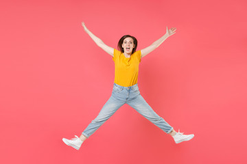 Full length portrait of excited shocked young brunette woman 20s in yellow casual t-shirt posing jumping spreading hands and legs keeping mouth open isolated on pink color wall background studio.