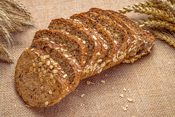 Home baked bread. Rye bakery with crusty loaves and crumbs. Fresh rustic traditional bread with wheat grain ear or spike plant on natural cotton background. Design element for bakery product label.