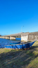 Local fishing boats moored on the shoreline of the Cavado River in Fao, Esposende, Portugal, with the Fao metallic bridge, known as D. Luís Filipe Bridge.