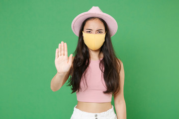 Young asian woman girl in casual pink clothes hat yellow face mask isolated on green background....