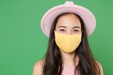 Close up of young asian woman girl in casual pink clothes hat yellow face mask isolated on green...