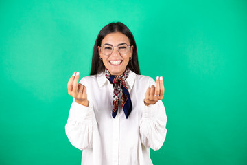 Young beautiful business woman over isolated green background doing money gesture with hands, asking for salary payment, millionaire business