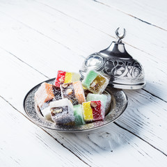 Turkish delight in a national metal plate with a lid and a crescent on a white wooden table.