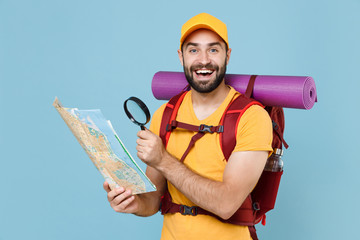 Cheerful young traveler man in yellow t-shirt cap backpack isolated on blue wall background....