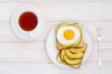 Healthy brekfast toasts with avocado and cup of tea on the white wooden background flat lay mock-up with copy space