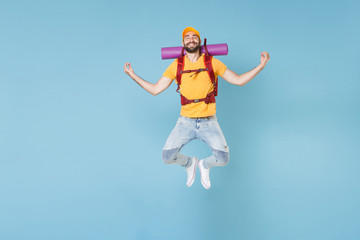 Full length portrait Smiling young traveler man with backpack isolated on blue background. Tourist traveling on weekend getaway. Tourism discovering hiking concept. Jump hold hands in yoga gesture.