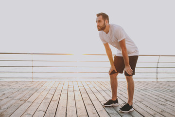 Full length portrait of handsome attractive young bearded athletic man guy 20s in white t-shirt...