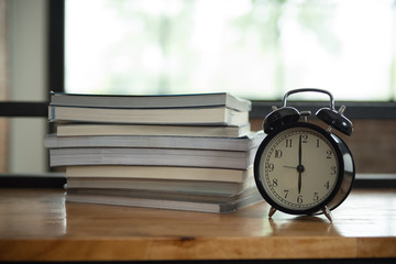  Stack of books with a black alarm clock on the table