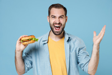 Angry irritated young bearded man guy 20s wearing casual clothes posing hold american fast food...